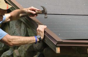 Person safely attaching outdoor lights to gutter clips from a stable ladder beside a suburban home.