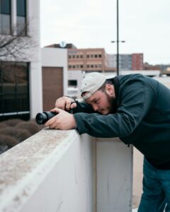 Homeowner photographs missing shingles and ceiling water stains after a storm while keeping repair receipts nearby.