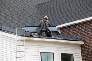 A residential roof showing asphalt shingles beside metal roofing panels under seasonal snow.